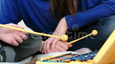 演奏<strong>音乐</strong>乐器。 特写男孩，他用棍子在<strong>木琴</strong>上演奏，他的老师坐在他附近。
